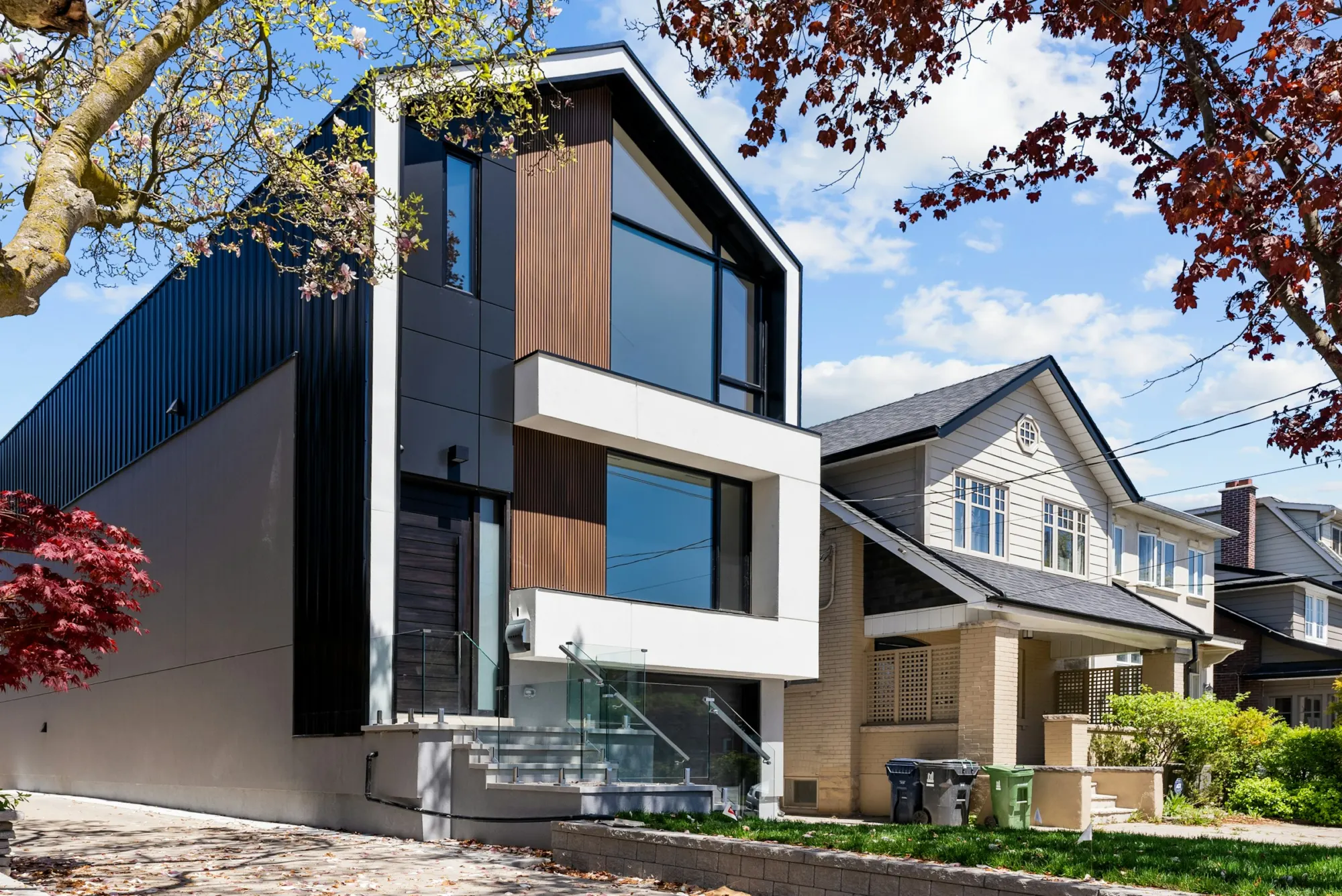 Modern two-story addition with dark siding next to a traditional house