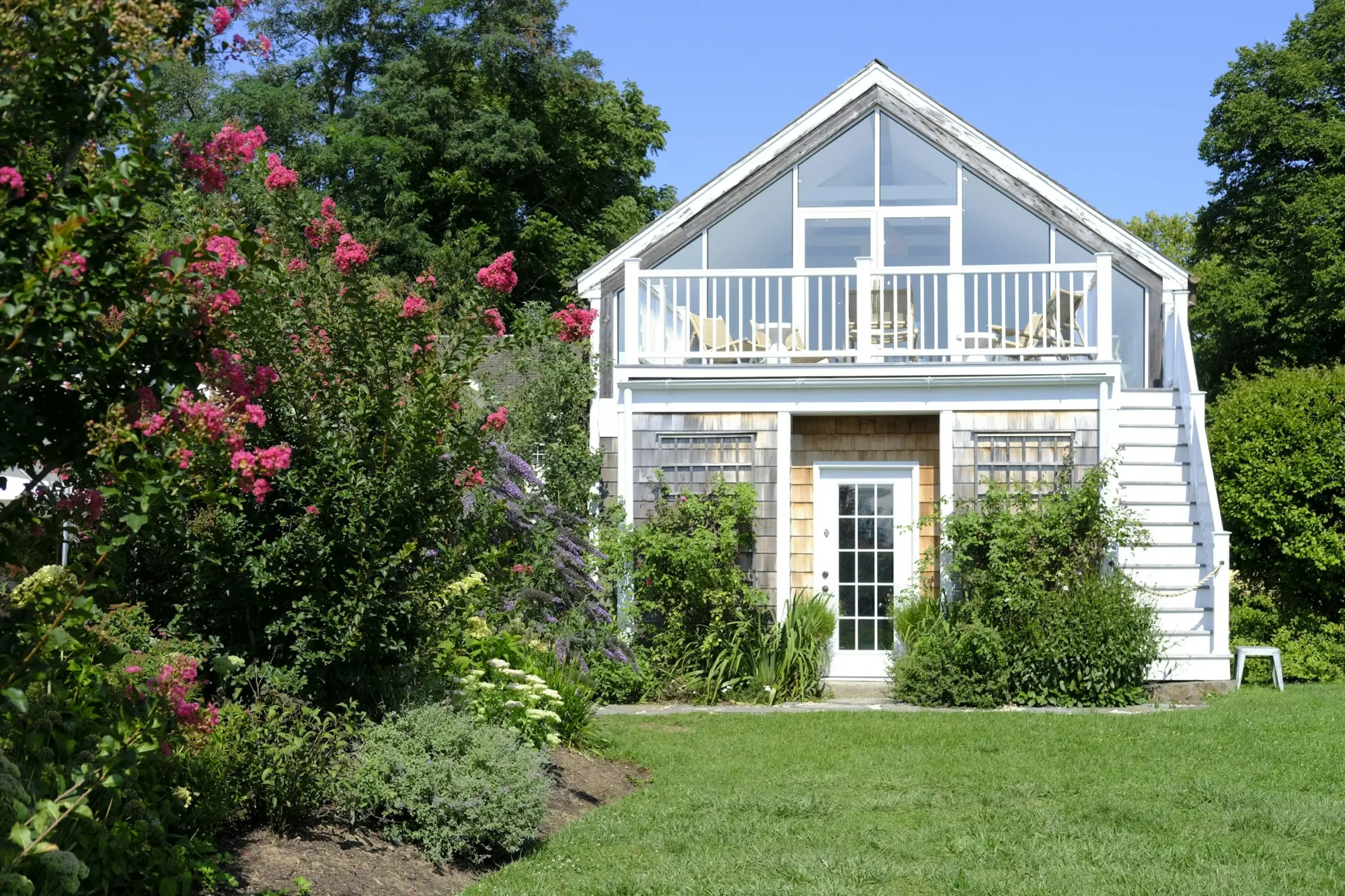 Two-story detached cottage with a glass gable and garden