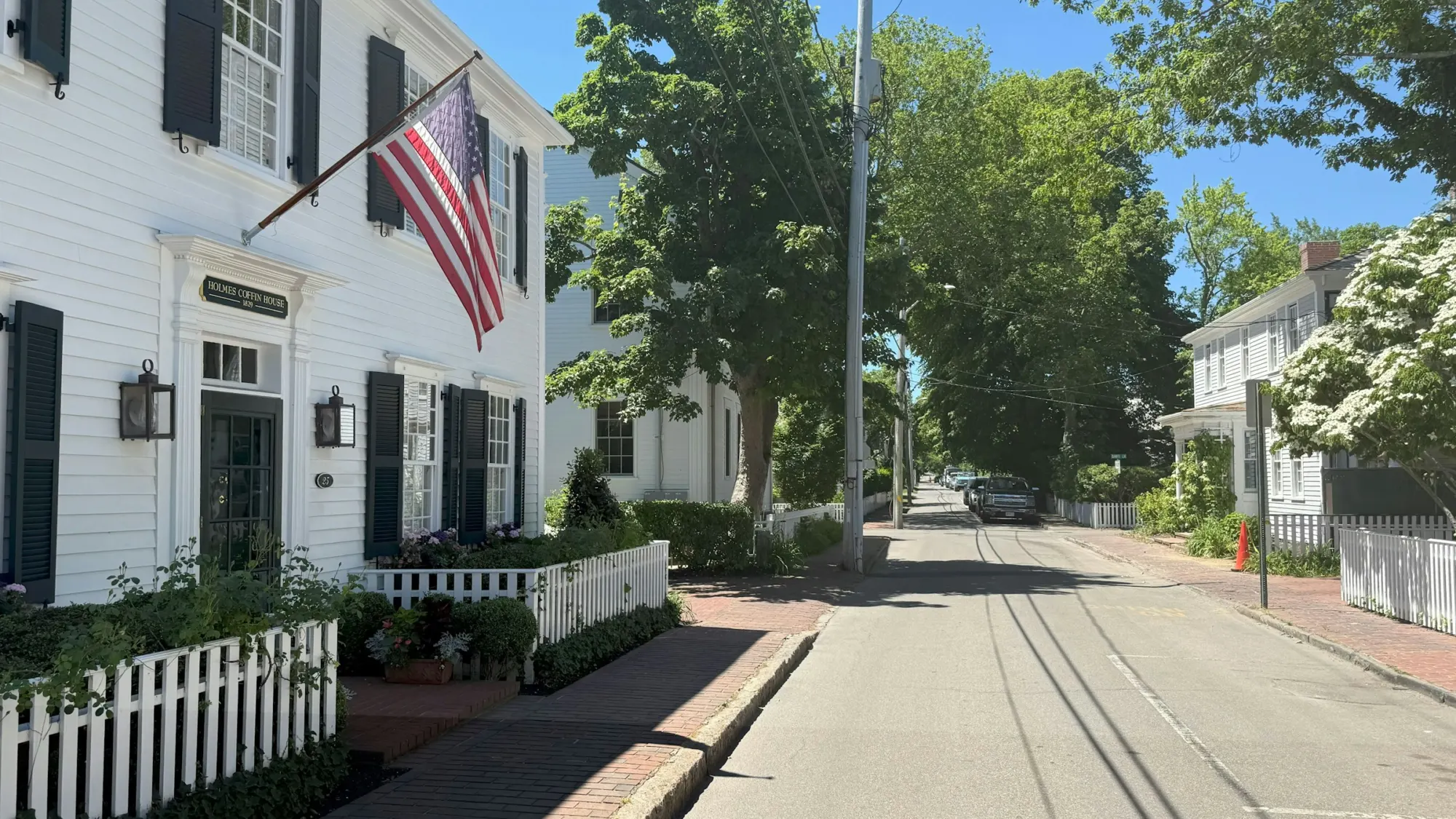 Residential street with a white colonial house and picket fence