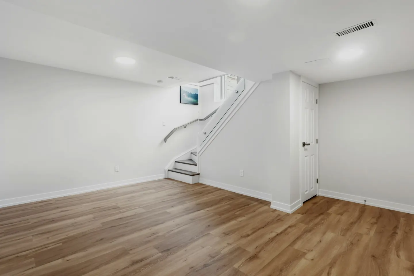 Finished basement with wood-look flooring and a staircase