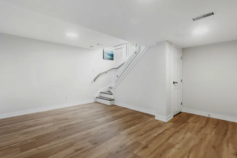 Finished basement with wood-look flooring and a staircase