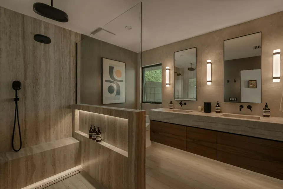 Bathroom with a wood double vanity, round mirrors and soft lighting