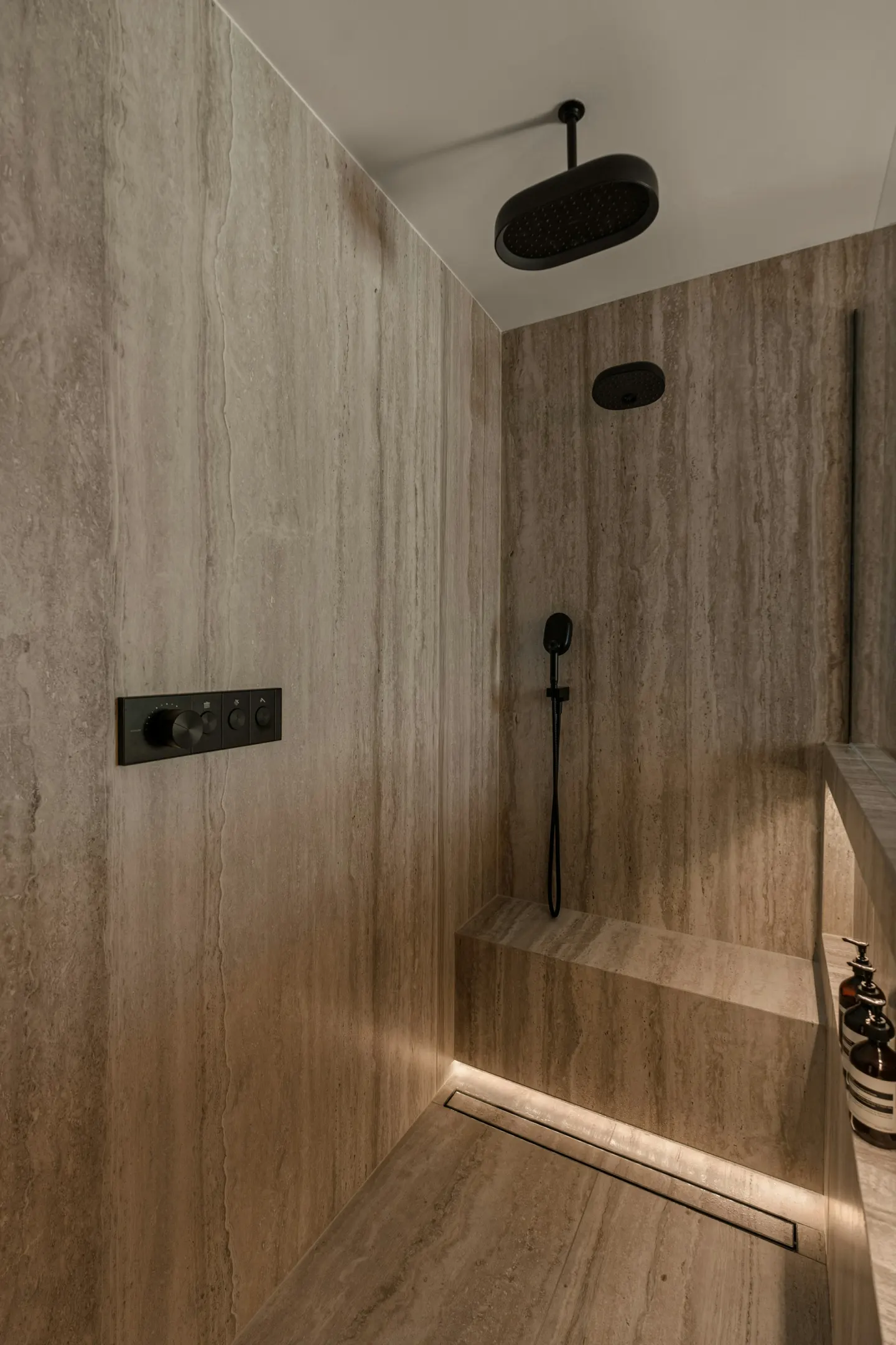 Shower with wood-look wall finish, niche lighting and black fixtures