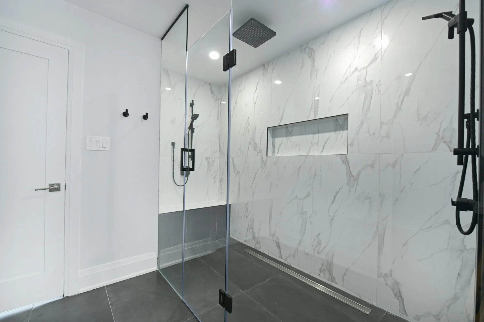 Walk-in shower with frameless glass and large-format marble wall tile