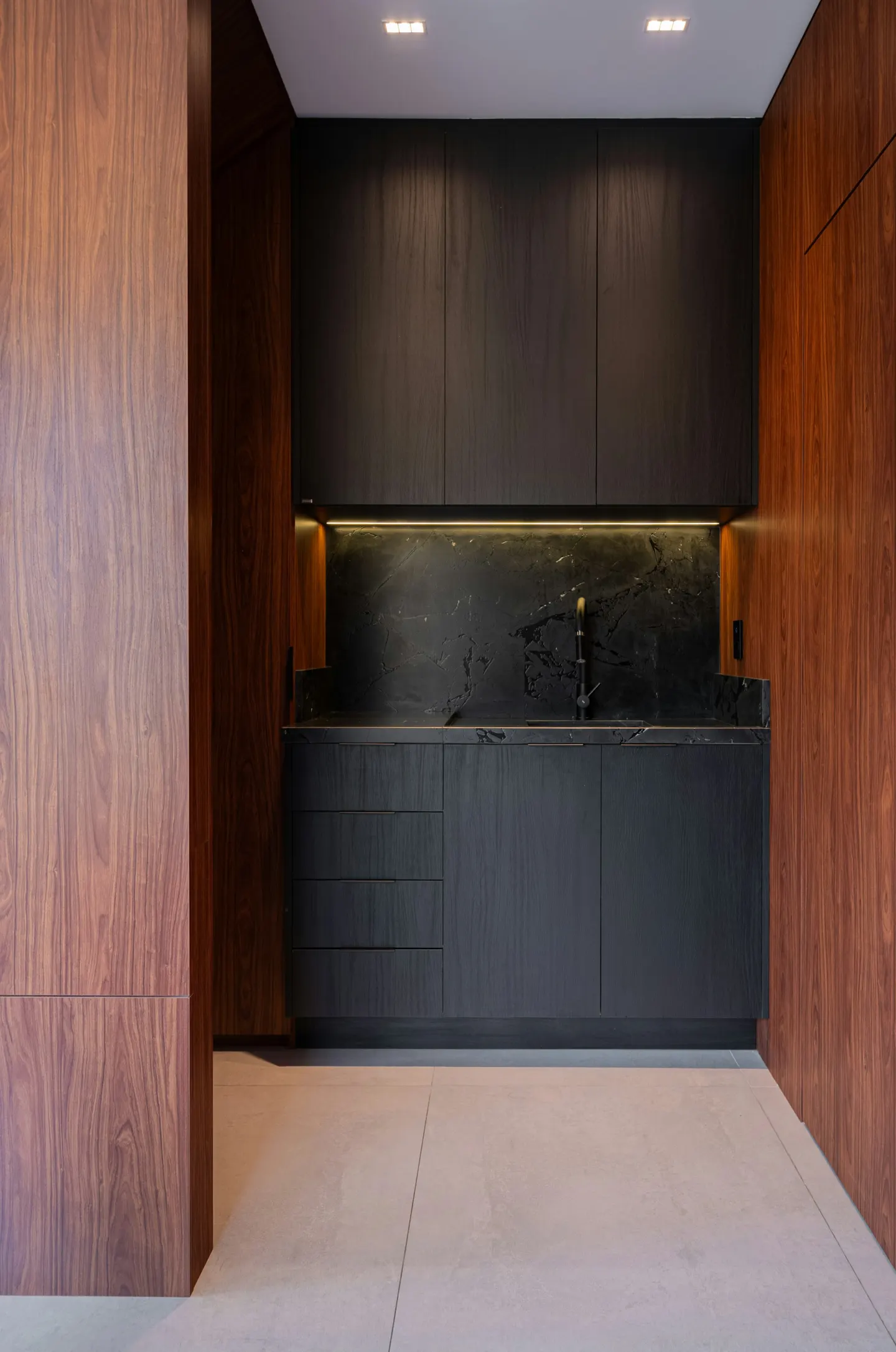 Built-in bar niche with dark cabinetry and stone backsplash